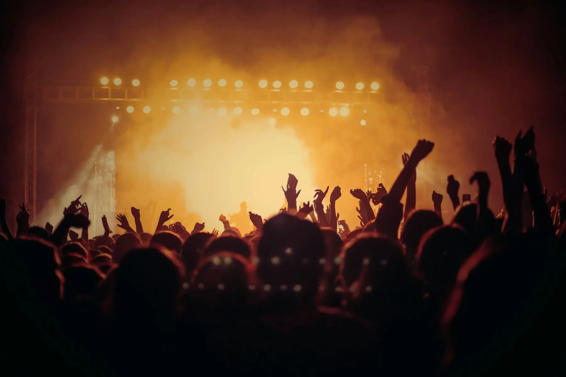 A concert crowd silhouetted against a glowing orange stage