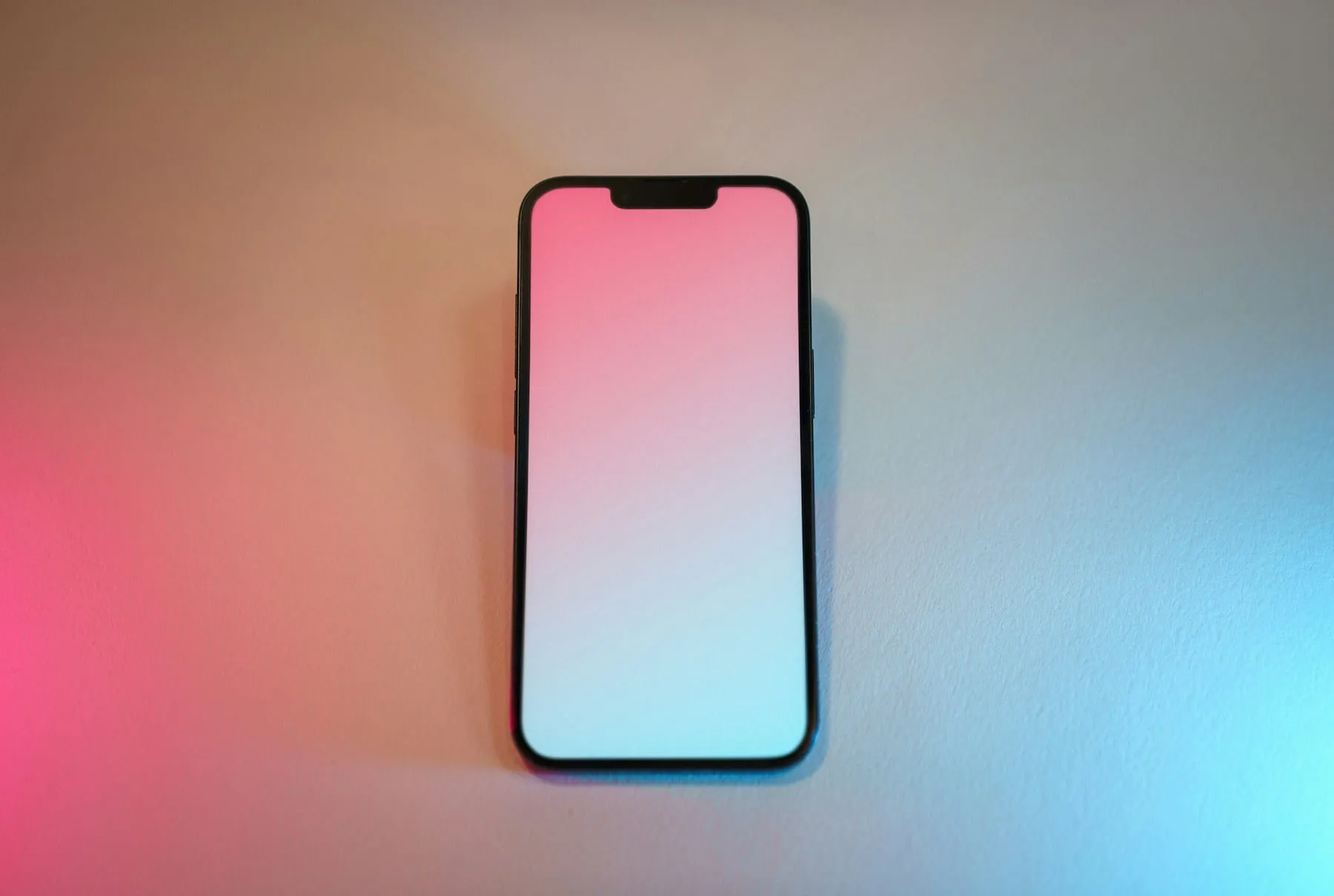 A pink and white smartphone sitting on a table