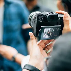 A photographer holding a camera with a candid street scene on the screen