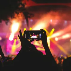 A phone recording a bright concert stage with pink and yellow lights