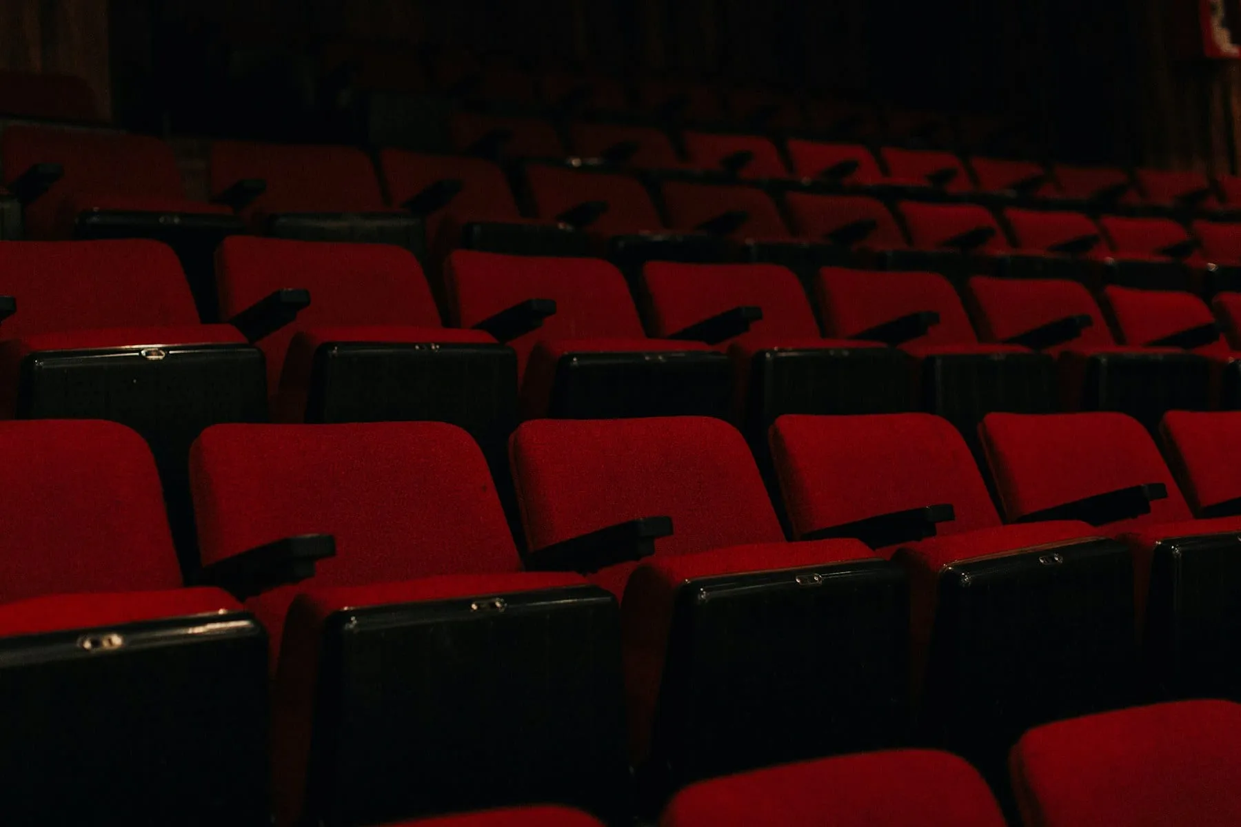 Rows of deep red seats in a dark cinema auditorium
