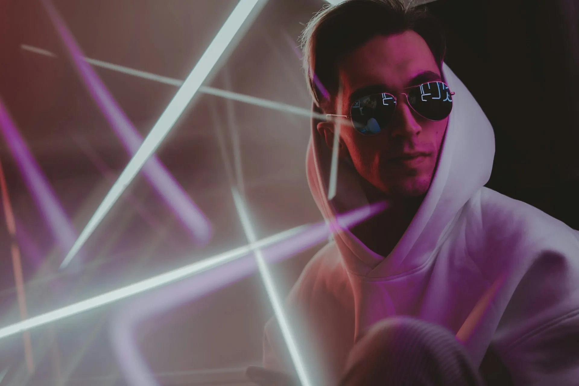 A woman in black sunglasses and a purple hoodie posing against a grey backdrop