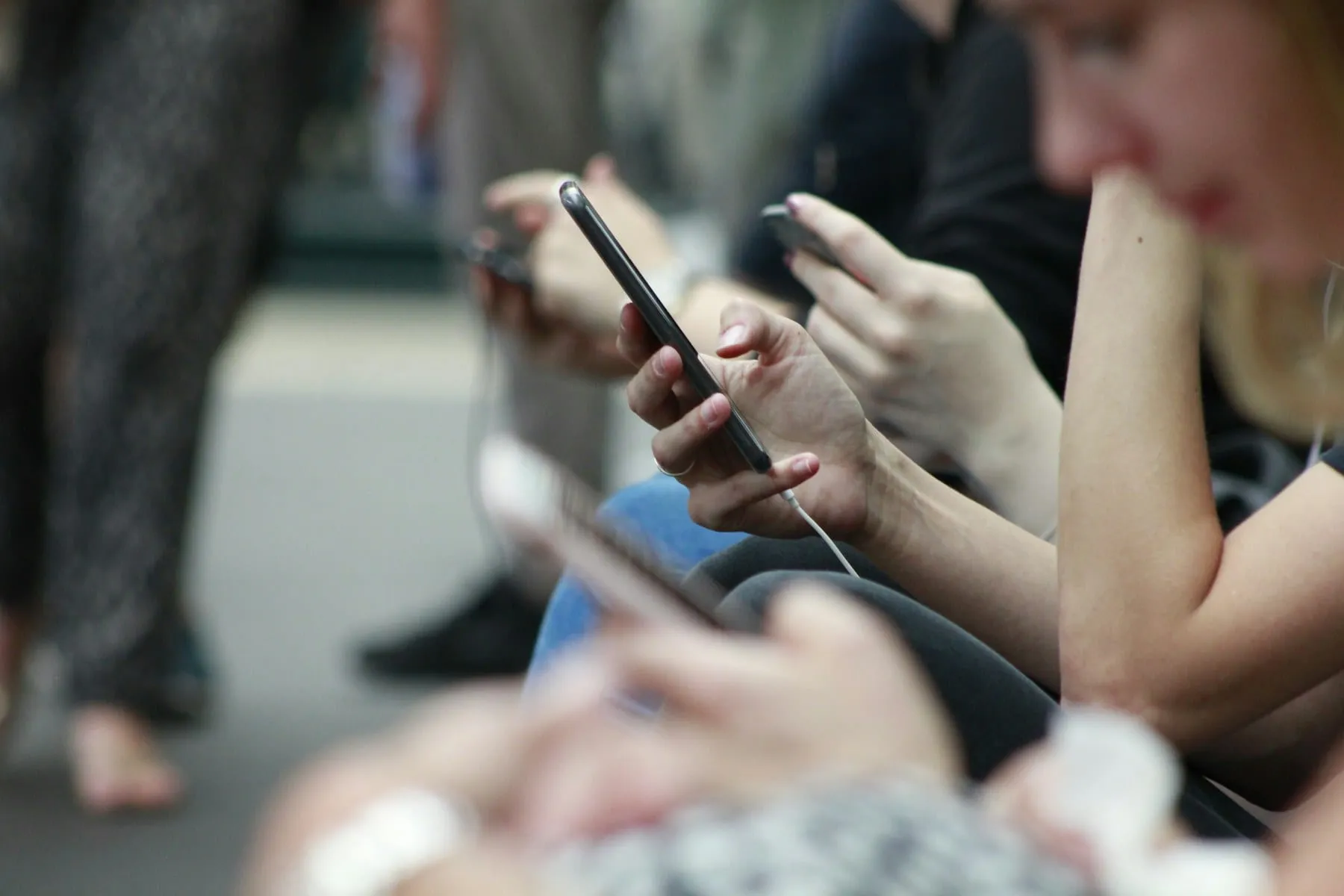 People sitting in a row while looking at their phones