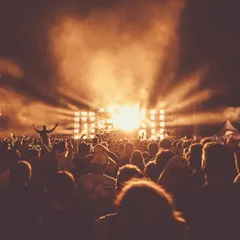 An outdoor festival crowd facing a blazing amber stage